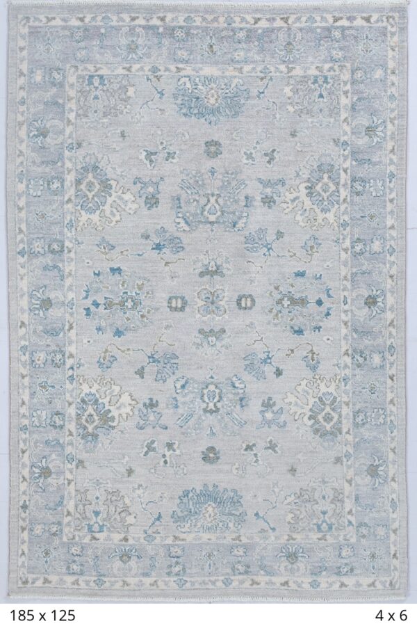 Handmade Chobbi area rug with grey ground color and blue border